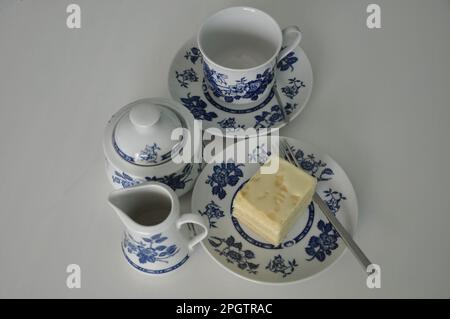 Cafetière tasse soucoupe gâteaux cuillère à sucre. Service complet de café sur fond blanc. Magnifique service de dîner blanc avec décoration bleue iso Banque D'Images