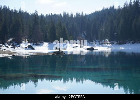 Deux personnes au sommet d'un rocher sur le lac, en regardant vers le lac avec fond de forêt enneigée Banque D'Images