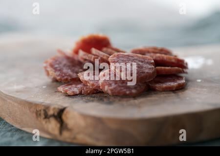 Saucisse séchée tranchée sur une planche de service d'olive, foyer peu profond Banque D'Images