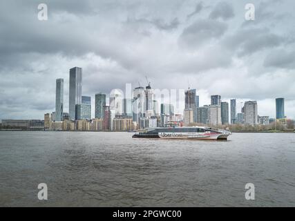 Un ferry Uber passe devant les gratte-ciel de Canary Wharf, l'un des quartiers financiers de Londres, près de la Tamise, en Angleterre. Banque D'Images