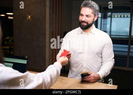 Touriste souriant recevant une carte-clé de la réceptionniste Banque D'Images