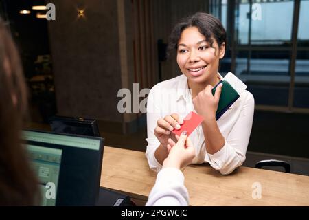 Une jeune femme souriante reçoit une carte-clé de la part d'un employé de la réception Banque D'Images