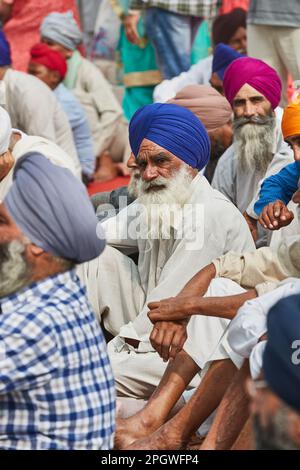 Amritsar, Punjab, Inde - Diwali 2019 - Sikh âgé avec une longue barbe blanche assise sur le sol entre autres hommes Banque D'Images