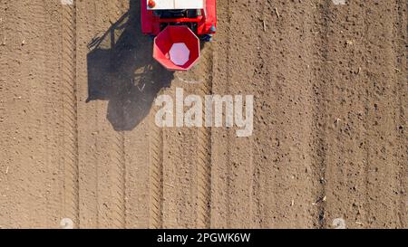 Vue de dessus du tracteur en position de lancement, fertilisation des terres arables pour les nouvelles récoltes, machine agricole traînante pour l'épandage de fertilisants artificiels Banque D'Images