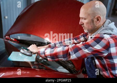 Un réparateur spécialisé installe le pare-brise sur la voiture Banque D'Images