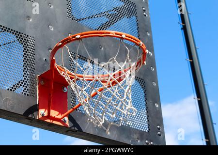 Panier de basket-ball public City Park à proximité avec fond noir en métal industriel et ciel bleu ensoleillé Banque D'Images