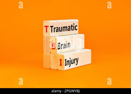 Symbole de lésion cérébrale traumatique TBI. Mots-clés TBI traumatisme crânien sur des blocs de bois sur une belle table orange fond orange. Médical an Banque D'Images