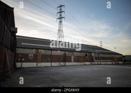 Ancien entrepôt à vide avec Pylon en arrière-plan, à Barking, dans l'est de Londres, tourné au crépuscule. Domaine industriel au crépuscule. Banque D'Images