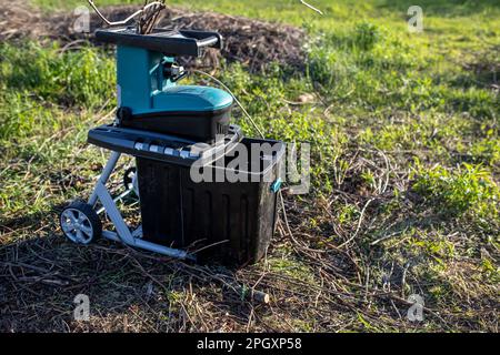 branches et vignes déchiquetées dans un conteneur broyeur électrique de jardin pour déchiqueter, un outil pour couper les déchets de bois et élaguer et lacer votre jardin Banque D'Images