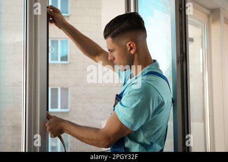 Un employé pose une bande de traction en caoutchouc sur la fenêtre Banque D'Images