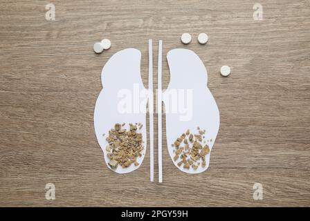 Découpe en papier des reins avec des pierres et des pilules sur une table en bois, plat Banque D'Images