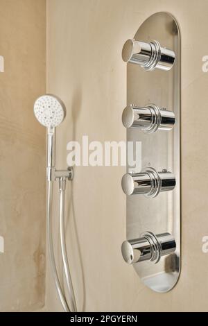 une douche murale avec deux combinés et une pomme de douche à main en arrière-plan est un mur de couleur havane Banque D'Images