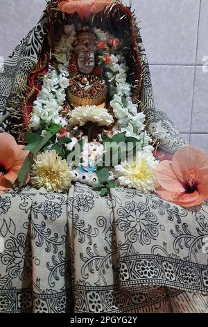 Vue sur l'idole de la déesse Lakshmi, vêtue de sari, décorée de fleurs et de guirlandes pour la réalisation de puja Banque D'Images