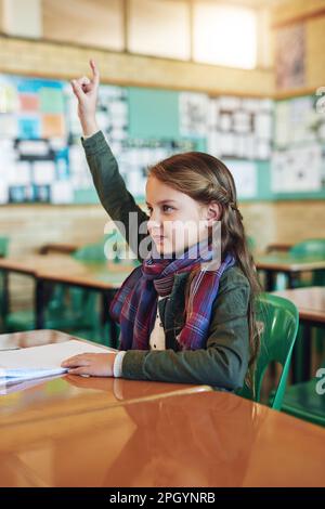 Ses n'ont jamais peur de poser des questions en classe. une adorable écolière de l'élémentaire qui lui lève la main en classe. Banque D'Images