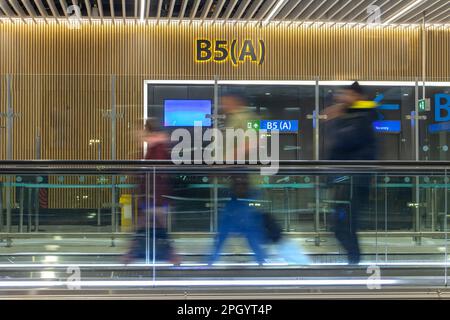 Les passagers se déplacent sur une passerelle mobile située dans le terminal de l'aéroport Banque D'Images