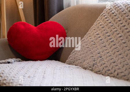 un canapé gris et un oreiller en forme de coeur rouge dans un appartement Banque D'Images