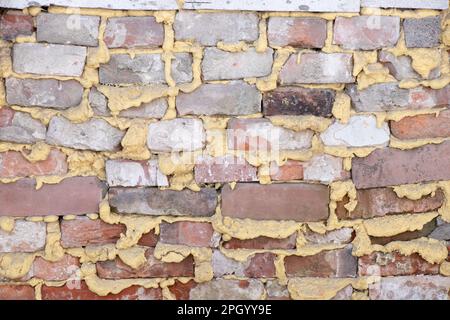 brickwork avec une couche intermédiaire remplie de mousse de construction comme un fond, vieux mur, rénovation Banque D'Images