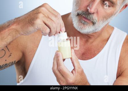 Beauté, soin de la peau et sérum de visage avec l'homme en studio pour l'anti-âge, les cosmétiques et les soins de spa. Produit, acide facial et hyaluronique avec modèle senior Banque D'Images