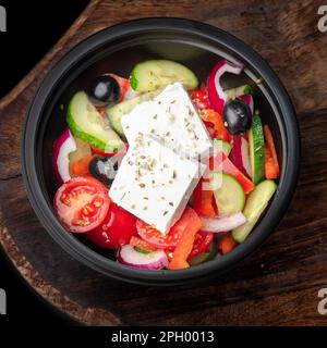 Salade grecque fraîche avec poivre, tomate, olive, feta. Pour aller salade dans un arc noir, plat sur un plateau, espace de copie, nourriture pour le menu et la publicité. clos Banque D'Images