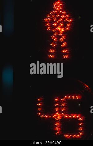 Le feu de circulation de passage pour piétons avec minuterie indique un signal d'arrêt rouge avec un panneau d'homme à LED sur fond noir de nuit, photo verticale en gros plan Banque D'Images