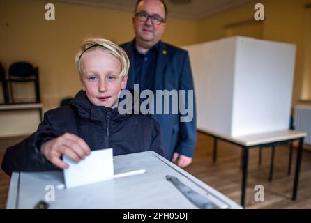 Grambow, Allemagne. 25th mars 2023. Philip Baltrusch (l), âgé de dix ans, met dans les urnes son bulletin de vote pour l'élection du maire de la ville de Grambow et est accompagné de son père Sven Baltrusch. L'objectif de l'élection est de reconnaître les préoccupations des enfants et des jeunes et des associer directement à la mise en œuvre des projets. Les enfants et les jeunes âgés de 6 à 16 ans sont appelés à voter. Credit: Jens Büttner/dpa/Alay Live News Banque D'Images