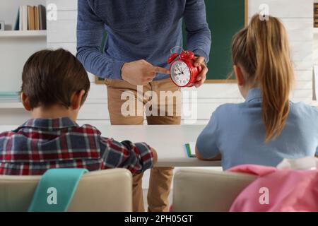Professeur avec un réveil qui fait entrer les élèves en retard dans la salle de classe Banque D'Images