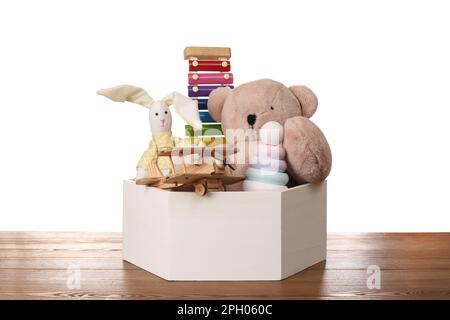 Jeu de jouets différents dans une boîte sur une table en bois sur fond blanc Banque D'Images