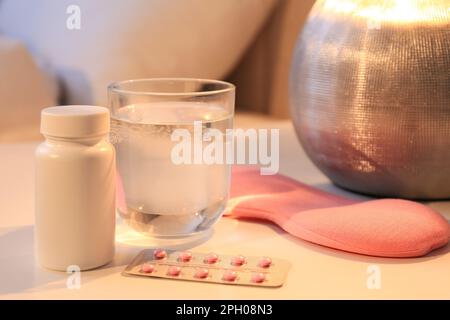 Masque de sommeil, pilules et verre d'eau sur la table de nuit à l'intérieur. Traitement de l'insomnie Banque D'Images