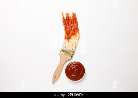 Pinceau à spaghetti trempés dans du ketchup sur fond blanc, vue de dessus. Concept créatif Banque D'Images