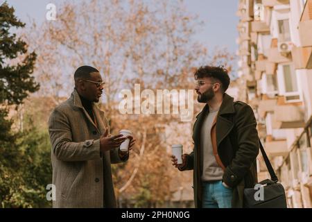 Divers collègues masculins, programmeurs, discutant de la façon d'erreur dans le code peut être résolu. Ils traînent et ont du café après le travail Banque D'Images