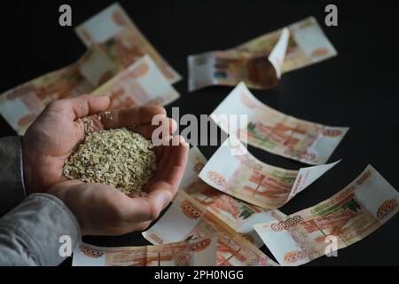 Le concept du coût du grain. 5000 roubles de billets autour d'une poignée de grain de terre. La faim dans le monde. Banque D'Images