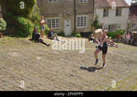 Les concurrents de la course de fromages Ladies portent leurs fromages sur Gold Hill, Shaftesbury, lors du festival de la gastronomie et des boissons de la ville, le 8th mai 2022. Banque D'Images