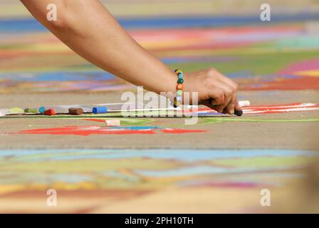 Un artiste fait de belles œuvres d'art dans la rue en utilisant la craie pastel tout en assistant au festival Madonnari Banque D'Images