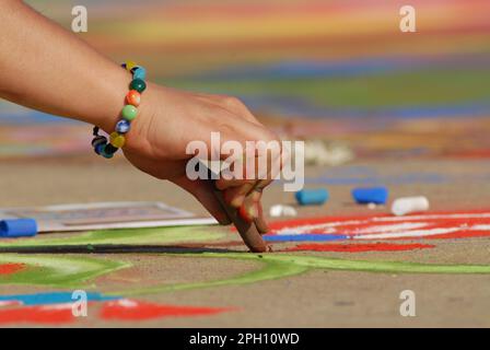 Un artiste fait de belles œuvres d'art dans la rue en utilisant la craie pastel tout en assistant au festival Madonnari Banque D'Images