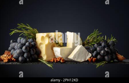 Fromage aux noix, raisins bleus et romarin sur fond sombre. Copier l'espace. Banque D'Images