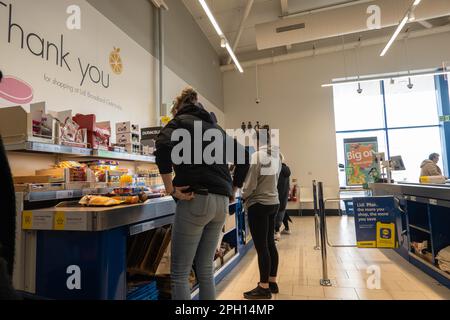 Les clients qui attendent des caisses au supermarché Lidls y magasinent sur un tapis roulant Banque D'Images