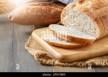 Pâte de pain en tranches sur plaque de bois et fond de bois, concept de boulangerie maison Banque D'Images