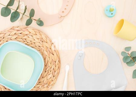 Accessoires pour bébés et vaisselle pour les repas sur fond beige. Concept de première alimentation pour enfants. Flat lay, Top View, Space for text. Vaisselle en silicone, bi Banque D'Images