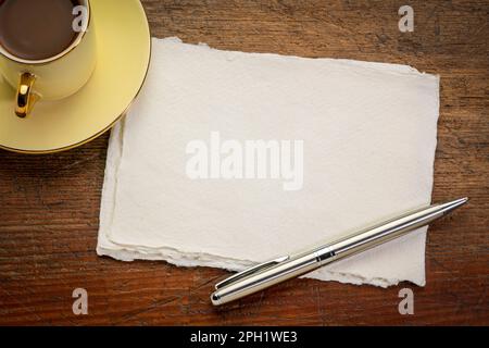 Petite feuille de papier chiffon blanc Khadi vierge sur table rustique en bois avec café Banque D'Images