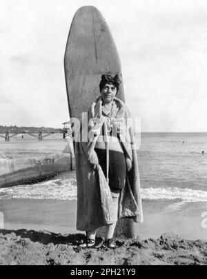 Portrait vintage d'une femme touriste senior posant avec une planche de surf en bois sur la plage de Waikiki à Honolulu, Hawaï, dans le 1920s. Banque D'Images