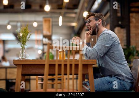 un jeune homme en ce moment aime la musique et boire du café Banque D'Images