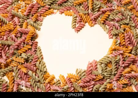 Pâtes de légumes de riz sur fond blanc, en forme de coeur, un lieu pour le texte. Banque D'Images