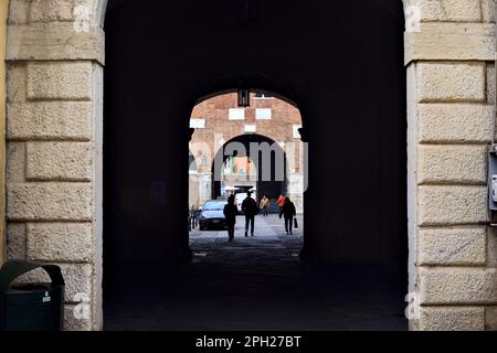 Allée couverte à l'ombre entre les places dans une ville italienne avec des gens passant Banque D'Images