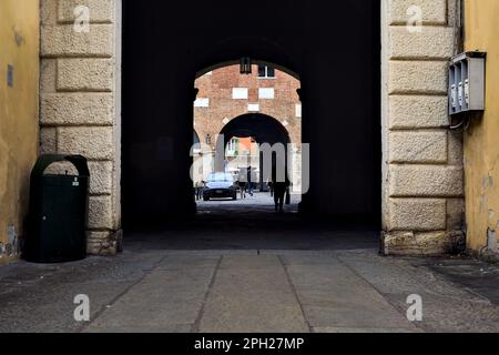 Allée couverte à l'ombre entre les places dans une ville italienne avec des gens passant Banque D'Images