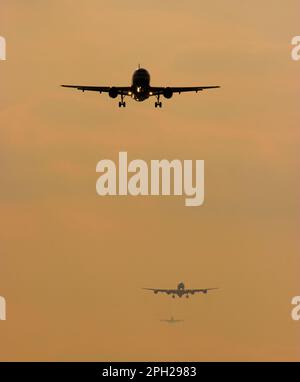 Trois avions sur l'approche finale de London Heahtrow au coucher du soleil. Banque D'Images