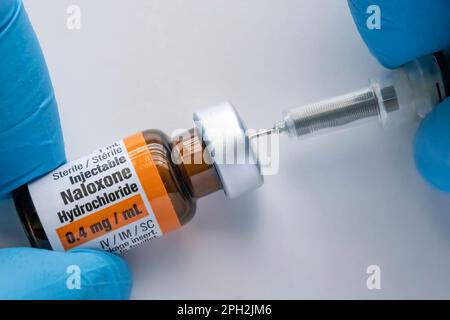 Calgary, Alberta, Canada. 25 mars 2023.Une personne utilisant un flacon de naloxone avec une photo du stock de seringues Banque D'Images