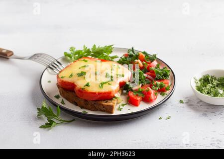 Délicieux petit déjeuner maison. Œufs frits au poivron rouge avec fromage, saupoudrés de persil haché avec de la tomate, de l'oignon rouge et de la salade verte sur un l Banque D'Images