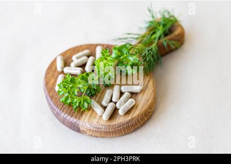 Les capsules de légumes et les branches de légumes verts reposent sur un petit panneau en bois, un concept d'additifs naturels Banque D'Images