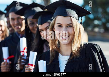 Prêt à commencer et à réussir notre carrière. Portrait d'un groupe d'élèves debout en ligne le jour de la remise des diplômes. Banque D'Images