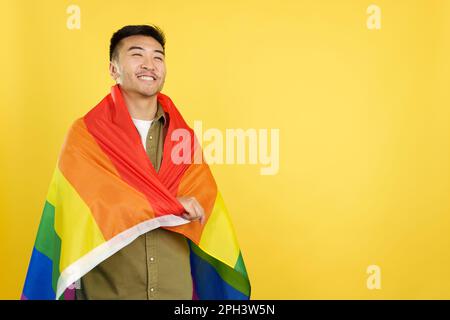 Joyeux chinois qui s'emparie d'un drapeau arc-en-ciel lgbt Banque D'Images